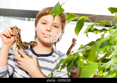 Il ragazzo si erge con sfera python contro la casa dei rettili Foto Stock