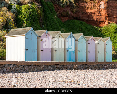 Mare Scena raffigurante una fila di variopinti ombrelloni, asfalto percorso, spiaggia di ciottoli e Jurassic Coast. Foto Stock