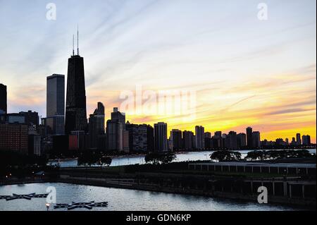 Chicago, Illinois, Stati Uniti d'America. Il sole tramonta tra le nuvole al di là di una porzione sullo skyline di Chicago lungo la città della Costa d'oro su un inizio serata d'estate. Foto Stock