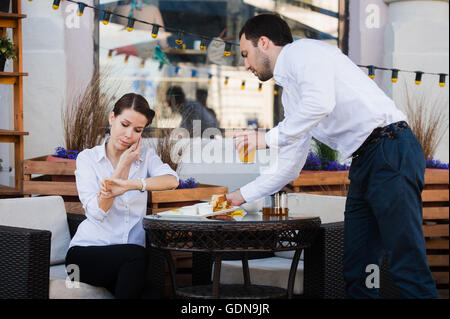 Server di cameriere al tavolo di lavoro nel menu lettura specials lista per donna Foto Stock