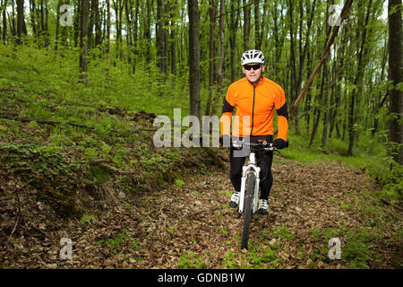 Ciclista in sella alla moto su un sentiero nella foresta di estate Foto Stock