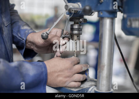 Close up dei lavoratori mani attacco di punta da trapano in officina Foto Stock