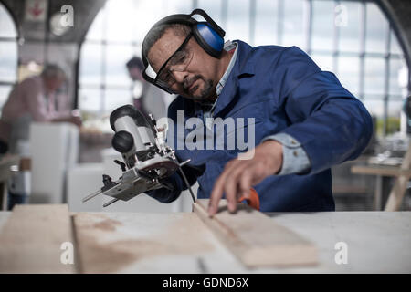 Carpenter utilizzando jigsaw attrezzo in officina Foto Stock