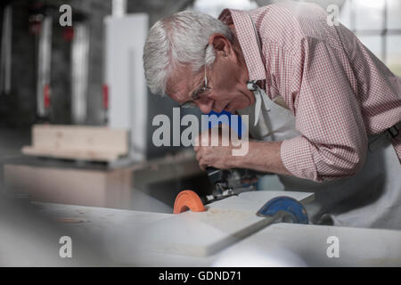 Senior falegname utilizzando jigsaw attrezzo in officina Foto Stock