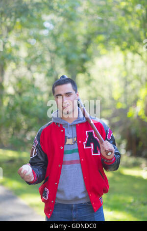 Ritratto di alta scuola senior in giacca, portando mazza da baseball e la sfera in posizione di parcheggio Foto Stock