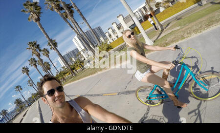 L'uomo prendendo selfie escursioni in bicicletta con la fidanzata a Venice Beach, California, Stati Uniti d'America Foto Stock