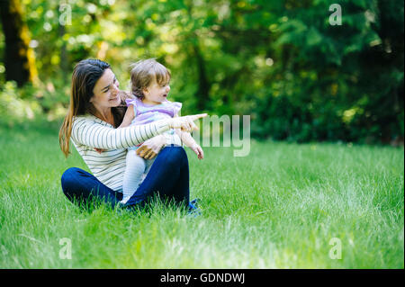 Donna seduta croce con zampe toddler figlia in posizione di parcheggio Foto Stock