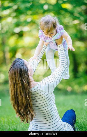 La donna sollevando il toddler figlia in posizione di parcheggio Foto Stock