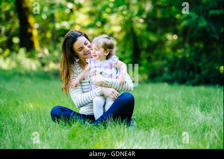 Donna abbracciando il toddler figlia in posizione di parcheggio Foto Stock