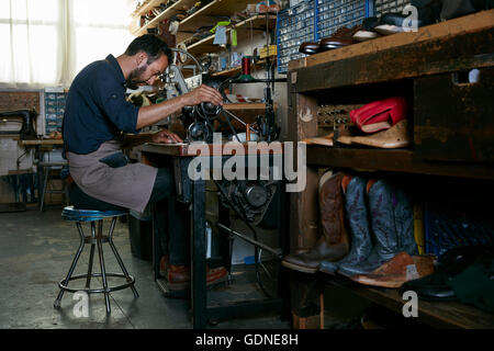 Cobbler maschio nella scarpa tradizionale workshop alla macchina da cucire Foto Stock