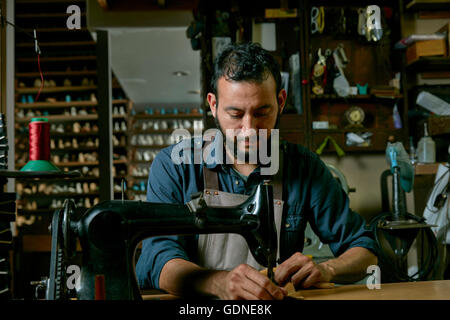 Cobbler maschio lavorando a macchina per cucire nella scarpa tradizionale workshop Foto Stock