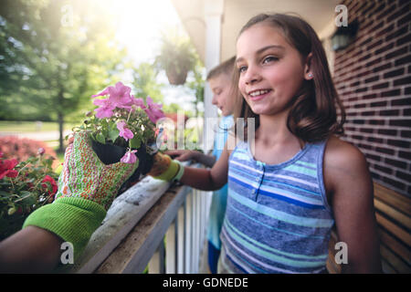 Mano indossando guanti da giardinaggio consegna impianto per un ragazzo e una ragazza Foto Stock