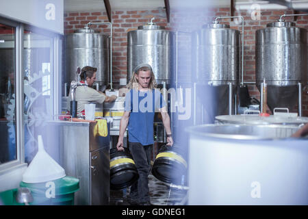 Uomo in microbirreria che trasportano barili di birra Foto Stock