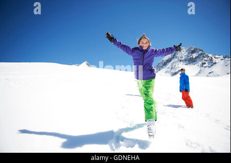 Ragazza adolescente jumping in snow, braccia tese Foto Stock