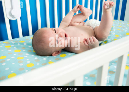 Carino da più di un mese il neonato si posa sulla sua schiena nel presepe, piangendo. Foto Stock