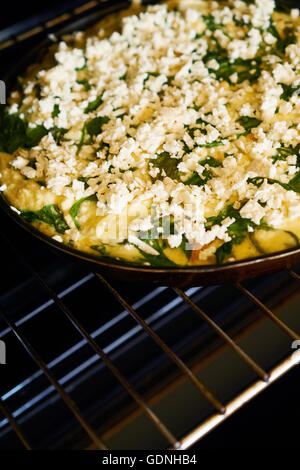 La cottura di un frittatat nel forno, uova, spinaci, pomodori e formaggio Foto Stock