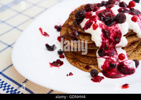 Gustose frittelle cercando su una piastra con yogurt e marmellata di frutti di bosco e salsa Foto Stock