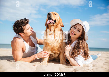 Giovani sorridenti matura in amore sdraiato sulla spiaggia con il cane Foto Stock