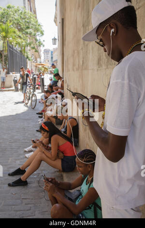 I giovani con un pubblico esterno hotspot wifi in calle Obispo, Havana, Cuba Foto Stock