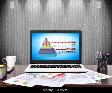 Computer portatile sul posto di lavoro con business piramide sullo schermo Foto Stock