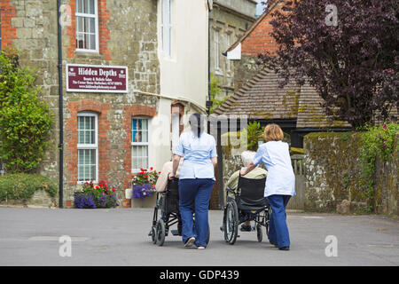 Gli anziani essendo prelevato in carrozzina a Shaftesbury, Dorset in luglio Foto Stock