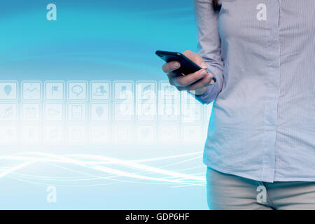 Giovane donna utilizzando il telefono cellulare e le icone digitali dietro di lei, metà sezione Foto Stock