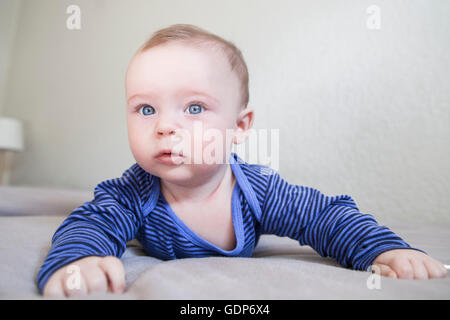 Blue eyed baby boy strisciando sul letto Foto Stock