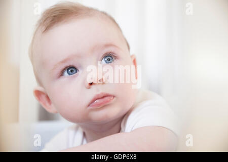 Ritratto di blue eyed baby boy decorrente dal presepe Foto Stock