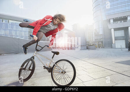 BMX Biker facendo stunt in area urbana Foto Stock