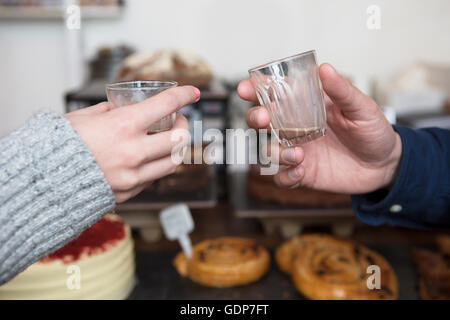 Chiusura del giovane con le mani in mano sollevando un espresso toast in cafe Foto Stock