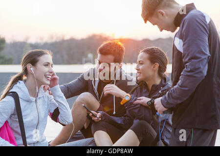 Quattro amici, indossare abbigliamento sportivo, chat, all'aperto Foto Stock