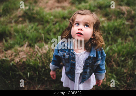 Giovane ragazza in piedi in campo, guardando verso il cielo Foto Stock