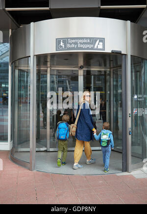 Vista posteriore della madre e figli tenendo la mano di entrare airport terminal Foto Stock