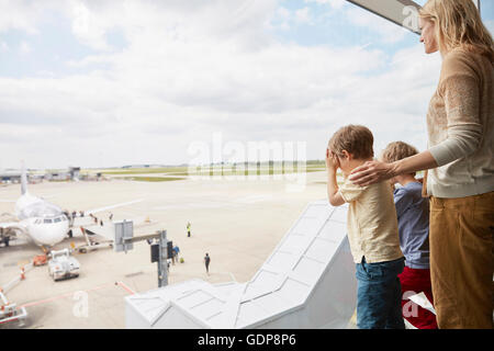 Madre e figli guardando fuori della finestra di airport Foto Stock