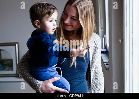 Metà donna adulta bambino portando figlio, puntamento Foto Stock