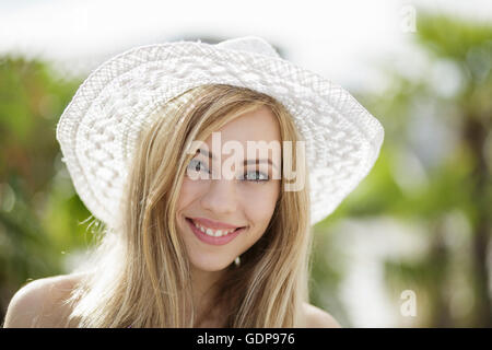 Ritratto della bella ragazza bionda che indossa cappello di paglia in città Foto Stock