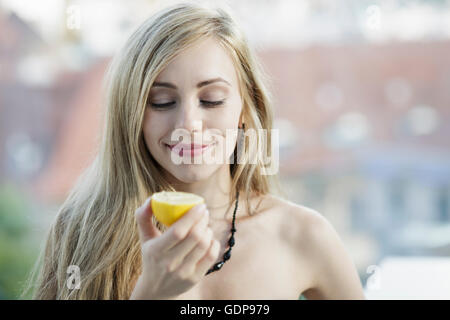 Capelli lunghi giovane donna bionda tenendo un limone Foto Stock