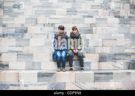 Due sorelle seduti insieme sulle fasi Foto Stock