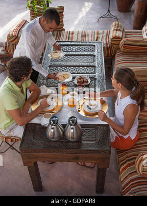 Cameriere che serve coppia giovane prima colazione, Marrakech, Marocco Foto Stock