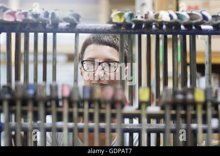 Vista attraverso il morsetto di appendere gli strumenti della donna in officina Foto Stock