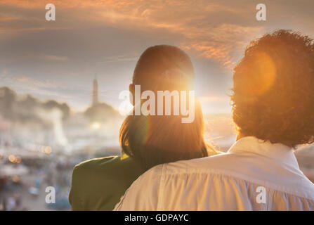 Vista posteriore del giovane guardando il tramonto sulla piazza Jemaa El Fnaa al tramonto, Marrakech, Marocco Foto Stock