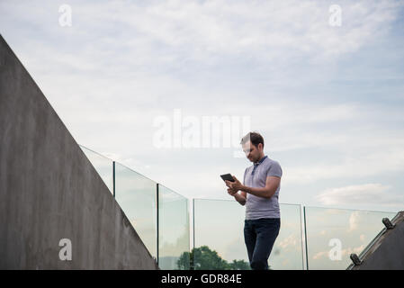 Giovane uomo nella ricerca di informazioni utilizzando un computer tablet. Foto Stock
