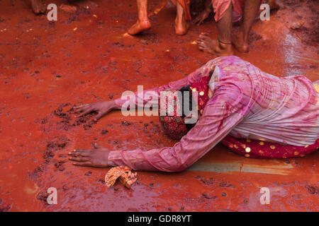 Nandgaon, India - 10 Marzo 2014: giovane maschio fiori di raccolta da terra e pregando durante holi celebrazione al tempio. Foto Stock