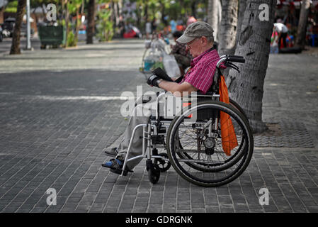 Uomo disabili in sedia a rotelle usando un portatile lettore di storia. Pattaya Thailandia SUDEST ASIATICO Foto Stock
