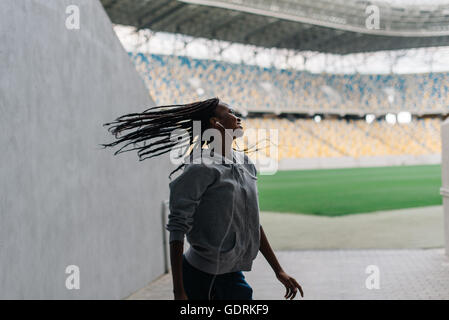 Giovani attraenti americano africano femmina oscillanti di ballo i suoi capelli intrecciati da soli a stadio vuoto Foto Stock