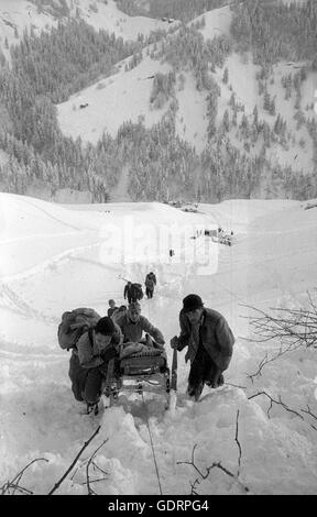 Squadra di salvataggio che trasportano una persona recuperato dopo le valanghe a Blons, 1954 Foto Stock