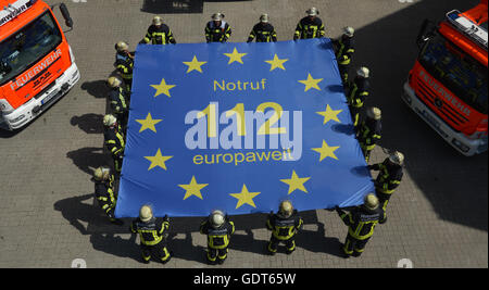 Stuttgart, Germania. 18 Luglio, 2016. Il personale dei servizi di emergenza dalla stazione dei vigili del fuoco 1 con in mano una bandiera con la scritta 'Notruf 112 europaweit' (lt. 'Chiamata di emergenza 112 in tutta Europa') a Stoccarda, Germania, 18 luglio 2016. Il 29 luglio 2016 la Comunità europea servizio di emergenza 112 celebra il venticinquesimo anniversario della sua fondazione. Foto: FRANZISKA KRAUFMANN/dpa/Alamy Live News Foto Stock