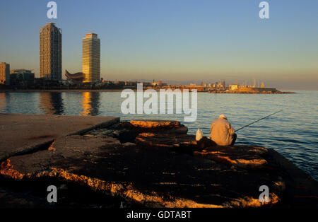 Barcellona: pescatore in jetty di gas (Barceloneta Beach). In Sfondo Torre Mapfre e Hotel Arts Foto Stock