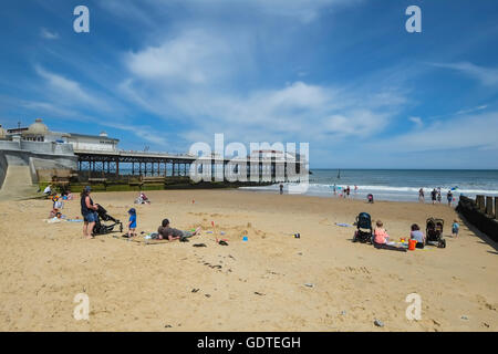 Persone rilassante sulla spiaggia accanto a Cromer Pier in Norfolk Foto Stock