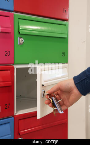 Un residente che apre e chiude una mail boxe nella lobby di un nuovo e moderno blocco di appartamenti in Deptford, a sud-est di Londra, Regno Unito Foto Stock